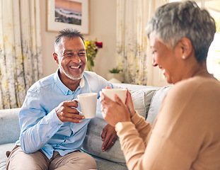Image showing Coffee, laughing and a senior couple on a sofa in the home living room to relax while bonding in conversation. Smile, retirement or love with a mature married man and woman talking while drinking tea