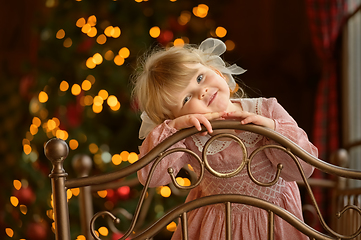 Image showing Little cute blond girl standing at headboard of iron bed