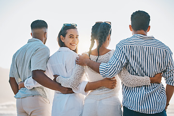 Image showing Happy friends, back and hug on beach for holiday, vacation or weekend together in nature. Rear view of group or people standing and bonding in community, support or trust by the ocean coast outside