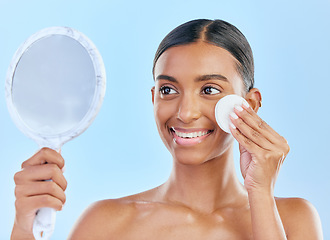 Image showing Mirror, cotton and woman with beauty or skincare as cosmetic product treatment isolated in a studio blue background. Cleaning pad, exfoliate and young female person with clean face due to facial