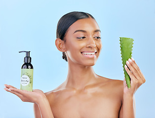 Image showing Woman, aloe vera and skincare in studio with smile, natural choice and happy by blue background. Girl, model and cactus plant for health, wellness and bottle with serum for self care, facial and glow