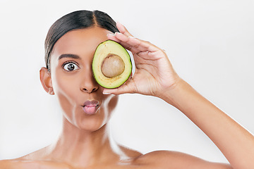Image showing Woman, avocado and funny studio portrait for health, wellness and diet for facial glow by white background. Girl, model and fruit for skincare, nutrition or cosmetics with comic expression for beauty