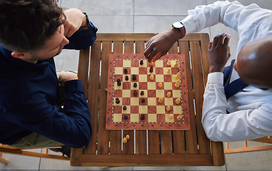 Image showing Chess, board game and men playing at a table from above while moving piece for strategy or challenge. Male friends together to play, relax and bond while moving icon for problem solving or checkmate