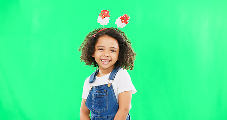 Image showing Portrait, children and cute with a girl on a green screen background in studio wearing a funky alice band. Kids, smile and innocent with an adorable little female child standing on chromakey mockup