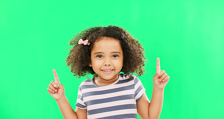 Image showing Face smile, girl child and pointing up on green screen in studio isolated on a background. Portrait, emoji and happy kid with hand gesture for mockup, advertising or marketing, branding or chroma key