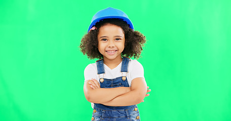 Image showing Little girl, face and smile in construction on green screen with safety helmet and arms crossed against a studio background. Portrait of small and happy child architect smiling on chromakey mockup