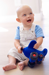 Image showing Happy little baby boy, toy and playing on floor in living room for fun childhood or development at home. Face of cute or adorable newborn child, kid or toddler enjoying play time with airplane toys