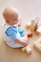 Image showing Little baby boy, toys and wooden blocks on floor for playtime, learning or childhood development at home. Cute, adorable or growing infant of newborn, child or toddler playing on the ground in house