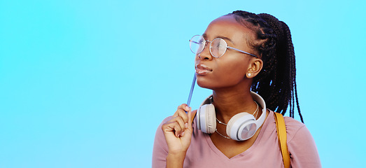 Image showing Black woman, thinking and gen z person with student vision and ideas in a studio copy space. Blue background, university students idea and headphones of a young female with glasses contemplating with