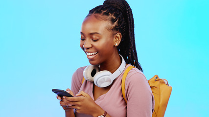 Image showing Phone, happy and black woman in a studio networking on social media, mobile app and the internet. Happiness, laugh and African female model typing a text message on a cellphone by a blue background.