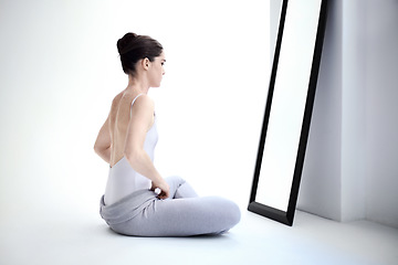 Image showing Female ballerina stretching by a mirror in a studio before a dance class, performance or concert. Art, creative and back of young ballet dancer doing a body warm up for classical dancing in her room.