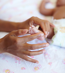 Image showing Hands, newborn and closeup of a baby foot with mother rubbing for comfort, care and love. Childcare, cute and zoom of a woman touching her premature infant child feet in her crib at their home.