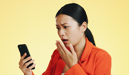 Image showing Asian woman, phone and shocked for bad news, loss or disbelief against a studio background. Female face in shock with facial expression on smartphone for terrible text, message or alert on mockup