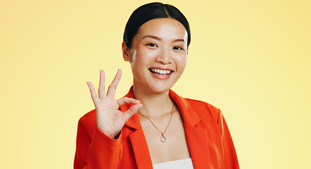 Image showing Smile, ok sign and face of Asian woman on yellow background for perfect, good job and agreement. Emoji mockup, hand gesture and portrait of happy girl in studio with success, okay symbol and yes icon