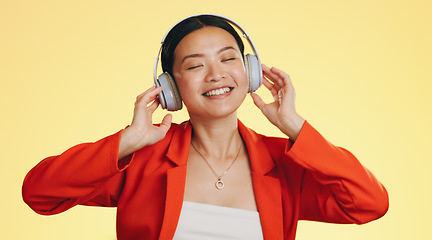 Image showing Dance smile, music headphones and woman in studio isolated on a yellow background. Technology, podcast or happy Asian female streaming, listening and dancing to radio, song and audio, sound and album