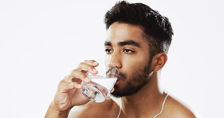 Image showing Man drinking water, hydration and health with serious face and glass in hand isolated on white background. Thirsty Indian male in studio, h2o and mineral with healthcare, wellness and mockup space