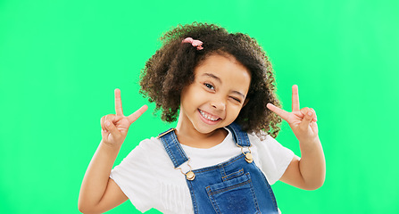 Image showing Face, smile and child with peace sign on green screen in studio isolated on a background. Portrait, emoji and wink of happy kid or girl with v hand gesture or symbol for happiness or joy.