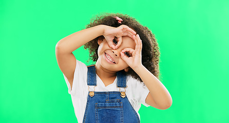 Image showing Green screen, happy and child with hands by eyes for glasses gesture for playing, happiness and fun. Emoji face, smile and portrait of girl with funny, comic and humour facial expression in studio