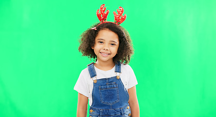 Image showing Children, christmas and a girl on a green screen background in studio wearing a reindeer antlers headband. Kids, portrait or festive with an adorable little female child feeling happy in the holidays