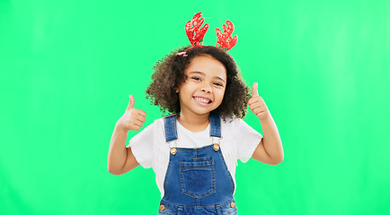 Image showing Happy, Christmas and thumbs up with girl in studio for holiday, festive and agreement. Approval, yes and like with child and deer headband on green background for satisfaction, smile and good news