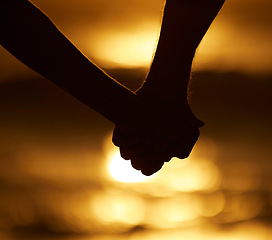 Image showing Couple, silhouette and holding hands at sunset on a beach for vacation or holiday outdoor. Closeup of man and woman in nature for peace, calm and love at ocean for creative shadow, travel or freedom