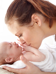 Image showing Mother, kiss and newborn baby in closeup with love, happiness and care in bedroom at family home. Young mom, infant child and hug with happy bonding, pride and together on bed in morning at house