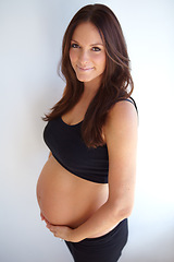 Image showing Woman, pregnancy portrait and tummy by wall with smile, excited or pride for new life, future or family. Young mom, pregnant and holding belly with happiness, love or care in house with expectation