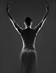 Image showing Creative, silhouette and back of a ballerina in a studio with elegant posture, pose or position. Art, monochrome and female ballet dancer doing a classical dance or performance by a black background.