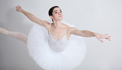 Image showing Focus, dance and ballet with a woman in studio on a white background for rehearsal or recital for theatre performance. Art, creative and balance with an elegant young ballerina or dancer in uniform