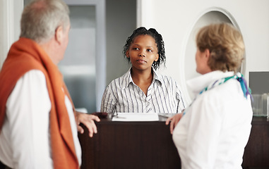 Image showing Hotel, reception and senior couple on vacation or elderly person at concierge, desk or check in with lobby receptionist or secretary. Black woman, working in hospitality and help people in retirement