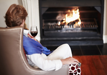 Image showing Relax, fire and senior woman with wine, home and comfortable with health, wellness and peace. Back, mature female person or old lady in a lounge, alcohol and warm for winter, weekend break or resting