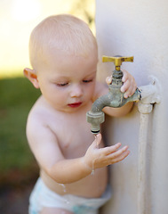 Image showing Outdoor, water and a baby playing at a tap in a summer garden at home. Little kid, childhood growth and adorable infant boy curious about faucet, washing hands and getting wet in backyard of a house