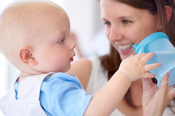 Image showing Playing, happy and a mother with a baby and water, bonding and care with a drink in a house. Smile, family and a mom holding a baby with a bottle for play, quality time or happiness together