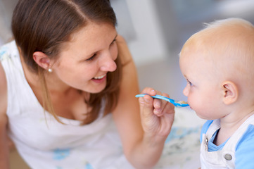 Image showing Mother, baby and feeding food, breakfast and eating for healthy nutrition in home. Happy mom, newborn and feed hungry child, infant or toddler meal with a spoon for growth, development and wellness.