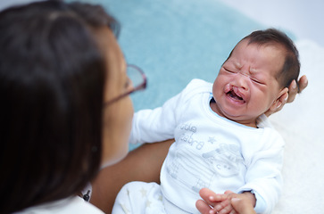 Image showing Crying, mother and a baby with a cleft lip in the bedroom of the home together for love or care from above. Healthcare, medical and child with a disability in the arms of a mom in a house for comfort