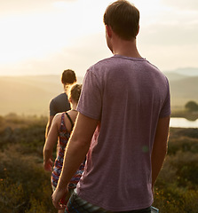 Image showing Friends, people hiking and trekking in countryside with fitness at sunset, nature with travel together and freedom. Exercise, adventure with men and woman walk through meadow or field with back view