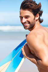 Image showing Portrait, surfboard and a surfer man at the beach in the ocean for surfing while on holiday or vacation. Face, smile and summer with a happy young male athlete shirtless outdoor by the sea for sport