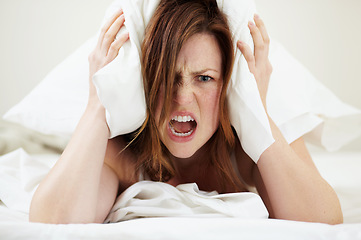 Image showing Portrait, angry and woman with pillow on ears to block noise, loud sound and sleep fail on bed in home bedroom. Face, person and covering head with cushion for insomnia, tired and frustrated scream.