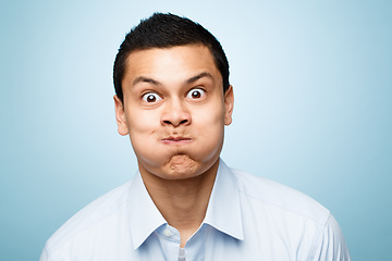 Image showing Comic, portrait of man with blowing cheeks and against a blue background. Blown mouth or mockup, surprised or fun and isolated male person with funny face expression against a studio backdrop