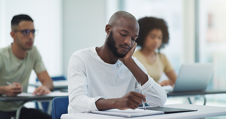 Image showing Black man, student desk and bored in university class with learning for college test at table. Book, school study and African male person thinking, writing and lecture notes for studying in classroom