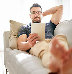 Image showing Tablet, sofa and man relaxing at his home reading a ebook or online blog on the internet. Rest, browsing and mature male person watching a video on social media with digital technology in living room