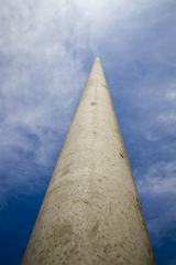 Image showing long concrete electric pole against the blue sky, close-up