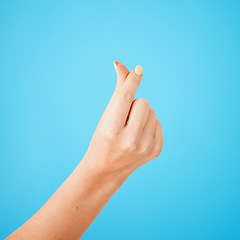 Image showing Gesture, hand sign for cash and money closeup on studio blue background for expensive, finance or currency. Person, thumb and index fingers rubbing together or symbol to pay, payment or poor salary