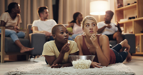 Image showing Friends, popcorn and movie at home at night for entertainment and relaxing for enjoyment. Friend, together and watching tv in the lounge with a snack in the evening to relax on the weekend for fun.