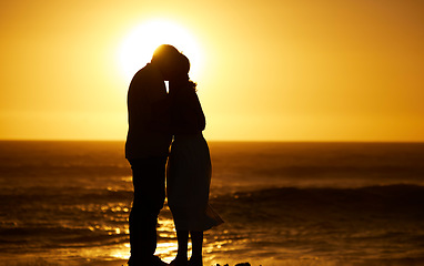 Image showing Couple, siilhouette and kiss at sunset on a beach for vacation, holiday or mockup outdoor. Romantic man and woman in nature with creative sky, care and ocean for love, shadow art and travel freedom