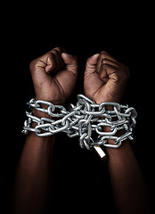 Image showing Chain, hands and prisoner of slavery isolated in studio on a black background. Chained, slave and hand of person in bondage, hostage or criminal in jail after arrest for crime, law and punishment.