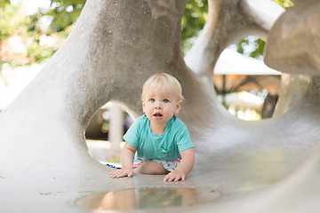 Image showing Child playing on outdoor playground. Toddler plays on school or kindergarten yard. Active kid on stone sculpured slide. Healthy summer activity for children. Little boy climbing outdoors.