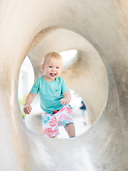 Image showing Child playing on outdoor playground. Toddler plays on school or kindergarten yard. Active kid on stone sculpured slide. Healthy summer activity for children. Little boy climbing outdoors.