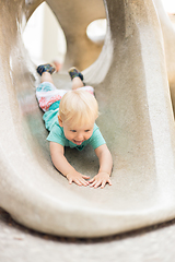 Image showing Child playing on outdoor playground. Toddler plays on school or kindergarten yard. Active kid on stone sculpured slide. Healthy summer activity for children. Little boy climbing outdoors.