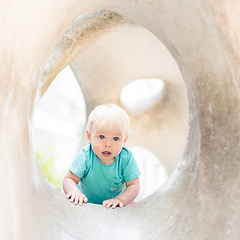 Image showing Child playing on outdoor playground. Toddler plays on school or kindergarten yard. Active kid on stone sculpured slide. Healthy summer activity for children. Little boy climbing outdoors.